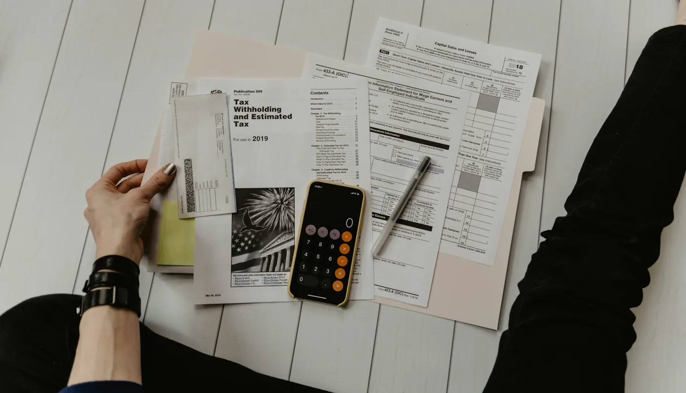 Hands reviewing real estate closing documents on a bright office desk